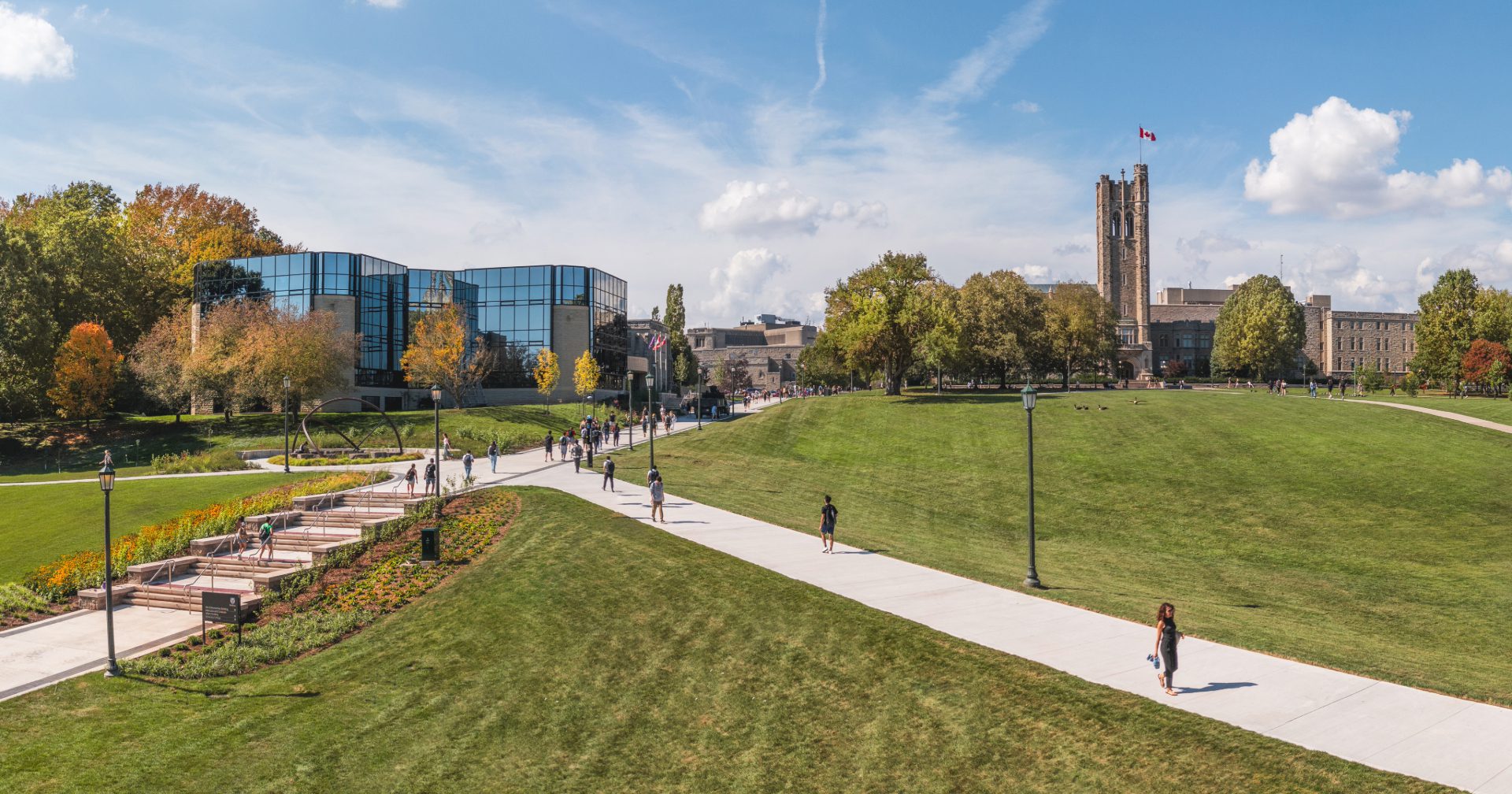 Colour photograph of Western campus with University College tower, students and a modern glass building